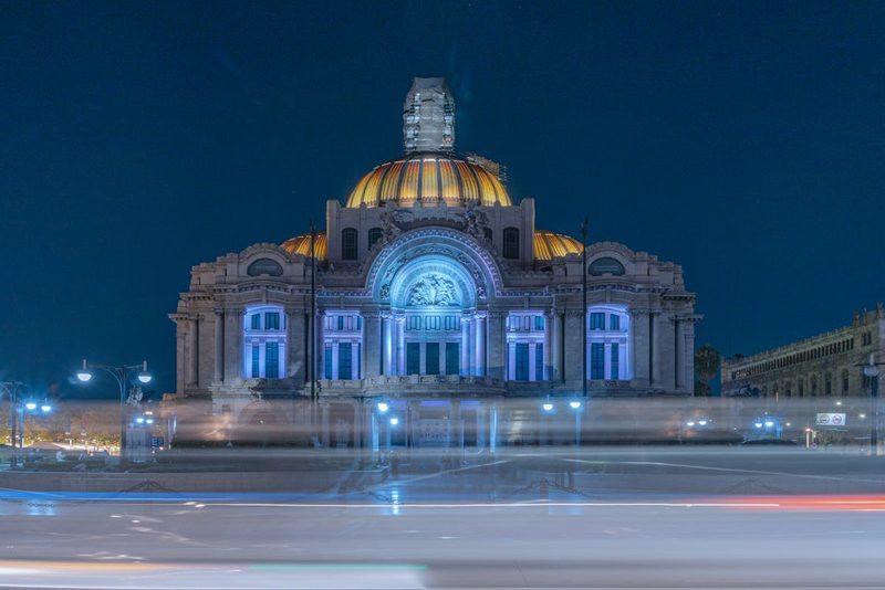 Illuminated Palacio de Bellas Artes at night with car light trails in Mexico City