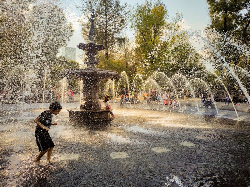 Children joyfully playing in a fountain at a park in Mexico City