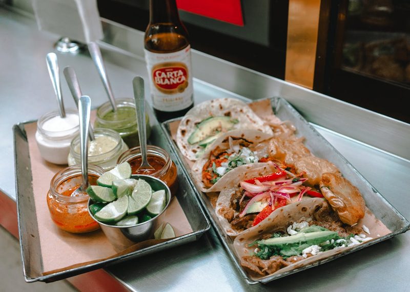 Delicious Mexican tacos served with sauces and lime paired with Carta Blanca beer in Mexico City