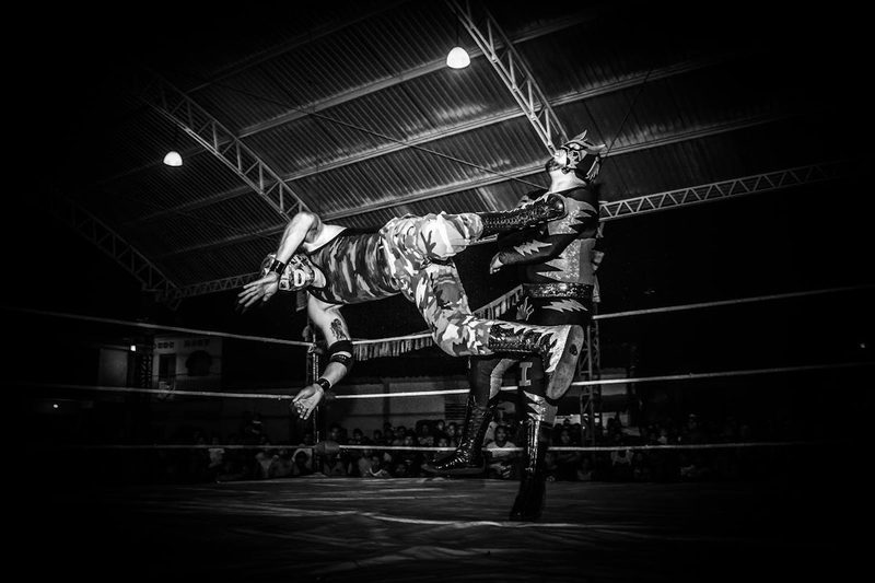 Intense Lucha Libre wrestling match showcasing strength and agility under dramatic lighting