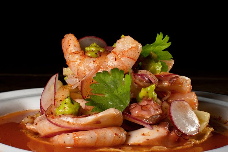 Delicious seafood platter featuring shrimp and octopus with spicy sauce and garnishes