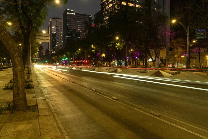 Vibrant nighttime view of Paseo de la Reforma boulevard with car light trails and illuminated skyscrapers